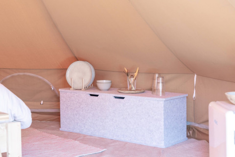 Innenansicht eines Zeltes im Little Canvas Escape mit Aufbewahrungskiste, Geschirr und Gläsern in Friesland.