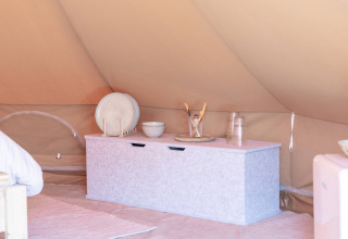 Interior view of a tent at Little Canvas Escape, featuring a storage chest, plates and glasses in Friesland.