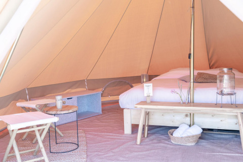 Interior de una tienda de glamping con cama y muebles en Little Canvas Escape, un parque vacacional en Friesland, Países Bajos.
