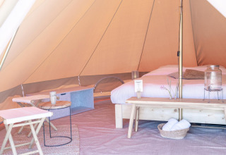 Interno di una tenda glamping con letto e arredi presso il parco vacanze Little Canvas Escape in Frisia, Paesi Bassi.