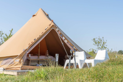 Tienda glamping con asientos exteriores en Little Canvas Escape, parque vacacional en Frisia, Países Bajos.