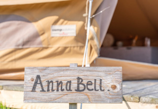 Cartello di legno con 'Anna Bell.' davanti a una tenda glamping a Little Canvas Escape, Frisia, Paesi Bassi.