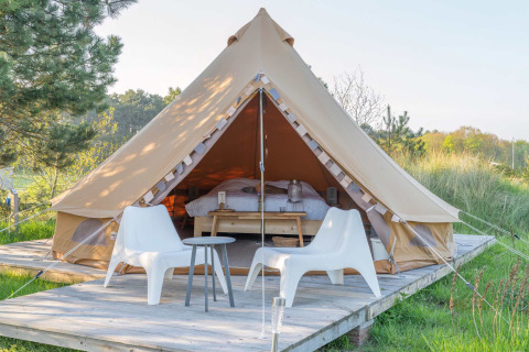 Luxuszelt mit zwei weißen Stühlen auf Holzterrasse im Little Canvas Escape, Friesland, Niederlande.