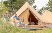 Dos personas se relajan frente a una tienda de glamping en el parque de vacaciones Little Canvas Escape en Frisia, Países Bajos.