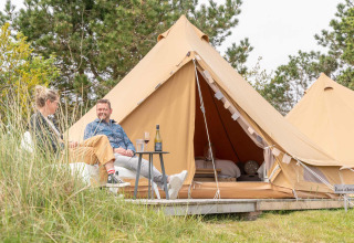 Twee personen genieten voor een glampingtent bij Little Canvas Escape, een vakantiepark in Friesland, Nederland.