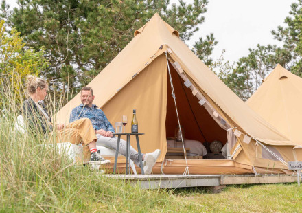 Twee mensen ontspannen voor een glampingtent bij Little Canvas Escape vakantiepark in Friesland, Nederland.