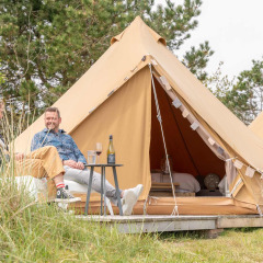 Dos personas se relajan frente a una tienda de glamping en el parque de vacaciones Little Canvas Escape en Frisia, Países Bajos.