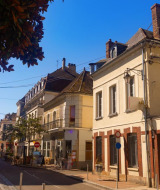 Calle pintoresca en un parque vacacional con glamping, casas encantadoras y cafeterías al aire libre soleadas.