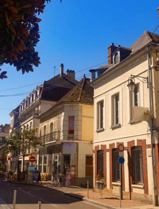 Calle pintoresca en un parque vacacional con glamping, casas encantadoras y cafeterías al aire libre soleadas.