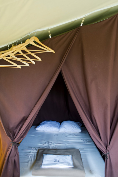 Inside view of Toile&Bois tent Sweet featuring a bed and hangers at Huttopia La Plage Blanche, France.