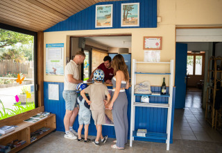 Familie tjekker ind ved receptionen på Camping Kost Ar Moor, feriepark i Bretagne, Frankrig, sommerdag.