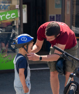 Un adulto ayuda a un niño con el casco de bicicleta frente a Camping Kost Ar Moor en Bretaña, Francia.