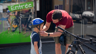 Un adulto ayuda a un niño con el casco de bicicleta frente a Camping Kost Ar Moor en Bretaña, Francia.