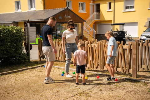 Een gezin speelt petanque op een speeltuin aan Camping Kost Ar Moor vakantiedomein in Bretagne, Frankrijk.