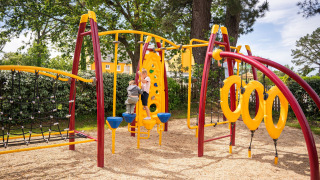 Área de juegos con estructura colorida y niños, destacado del Camping Kost Ar Moor en Bretaña, Francia.