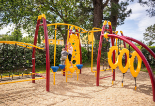 Playground with colorful climbing frame and kids, a highlight of Camping Kost Ar Moor in Brittany, France.