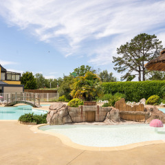 Piscina al aire libre con temática tropical en Camping Kost Ar Moor, parque de vacaciones en Bretaña, Francia.