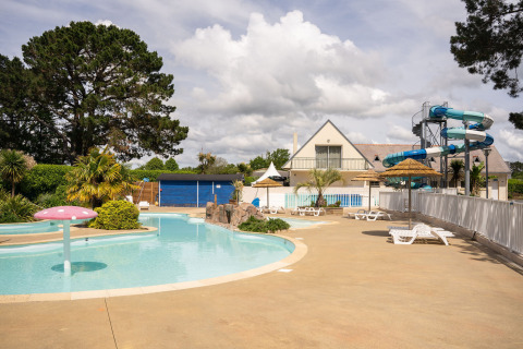 Zona de piscina exterior con toboganes de agua y tumbonas en Camping Kost Ar Moor en Bretaña, Francia.