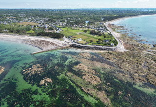 Luftfoto af Mousterlin i Fouesnant, Bretagne, Frankrig med kystlinje, strand, grønne marker og klare vande.