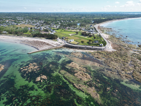 Luftfoto af Mousterlin i Fouesnant, Bretagne, Frankrig med kystlinje, strand, grønne marker og klare vande.