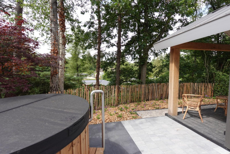 Ausblick von der Eco Cottage mit Whirlpool und Terrasse im De Thijmse Berg, umgeben von Bäumen, Niederlande.