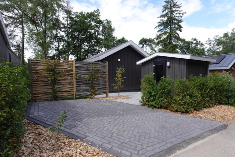 Miljøvenlig hytte med moderne design og boblebad på De Thijmse Berg i Holland, omgivet af grøn beplantning.