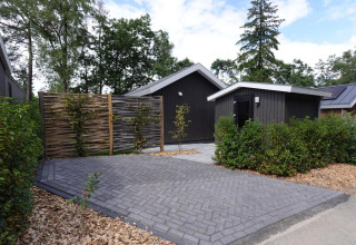 Eco Cottage met hot tub bij De Thijmse Berg in Nederland, moderne lodge omringd door groene beplanting.