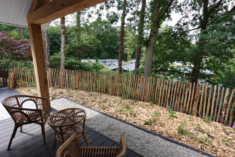 Blick von der Eco Cottage Terrasse in De Thijmse Berg, Niederlande, mit Holzzaun und Gartenmöbeln.
