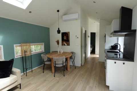 Sala y cocina modernas en una Eco Cottage con pared verde en De Thijmse Berg, Países Bajos.
