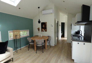 Moderne woonkamer en keuken in een Eco Cottage met groene accentmuur bij De Thijmse Berg, Nederland.
