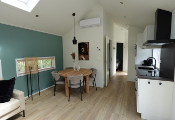 Moderne stue og køkken i Eco Cottage med grøn accentvæg på De Thijmse Berg, Nederlandene.