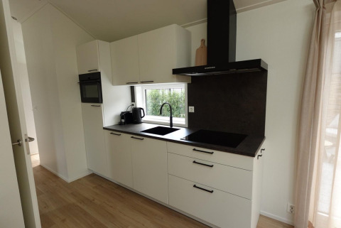 Cuisine moderne de l’Eco Cottage à De Thijmse Berg, Pays-Bas, avec armoires blanches et grande fenêtre.