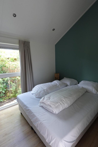 Dormitorio moderno en Eco Cottage + hot tub de De Thijmse Berg, Países Bajos, con gran ventanal y dos camas.