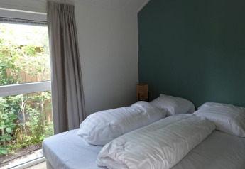 Moderne slaapkamer in Eco Cottage + hot tub bij De Thijmse Berg, Nederland, met groot raam en tweepersoonsbed.