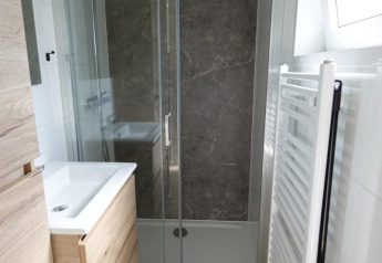 Modern bathroom featuring a shower, wood flooring, radiator, and window at Eco Cottage lodge in the Netherlands.