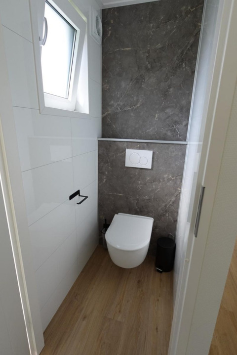 Salle de bain moderne à Eco Cottage + hot tub à De Thijmse Berg aux Pays-Bas, sol en bois, mur gris.