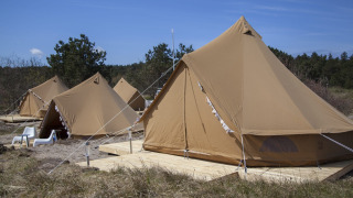 Varios tipis Bell Escape sobre plataformas de madera en la naturaleza, con sillas bajo el cielo azul.