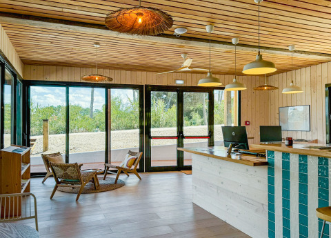 Receptie van Village Huttopia Lagoa de Óbidos in Portugal, met houten interieur en grote ramen naar de natuur.