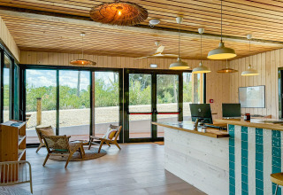 Receptie van Village Huttopia Lagoa de Óbidos in Portugal, met houten interieur en grote ramen naar de natuur.