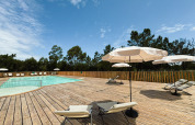Espace piscine en plein air avec transats et parasols sur terrasse en bois à Village Huttopia Lagoa de Óbidos.