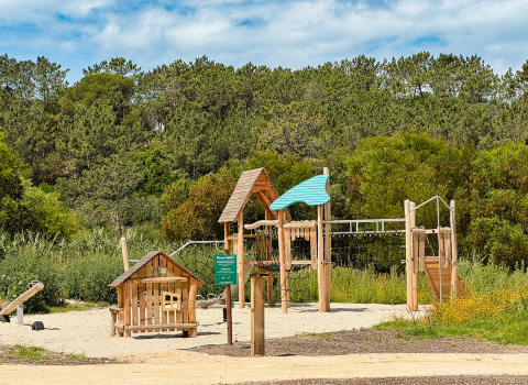 Parque infantil de madera rodeado de vegetación en Village Huttopia Lagoa de Óbidos, Portugal Central.