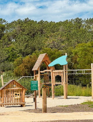 Parque infantil de madera rodeado de vegetación en Village Huttopia Lagoa de Óbidos, Portugal Central.