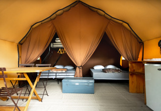 Vue intérieure d'une tente safari confortable avec lits et équipements à Village Huttopia Lagoa de Óbidos, Portugal.