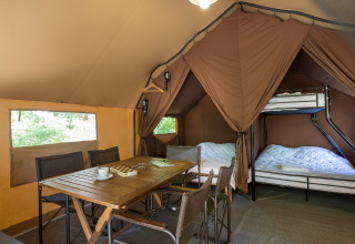 Interieur van een Canadian tent in Village Huttopia Lagoa de Óbidos, Portugal, met tafel, stoelen en bedden.