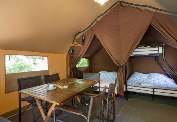 Interior of a Canadian tent at Village Huttopia Lagoa de Óbidos, Portugal, showing a table, chairs, and beds.