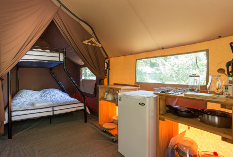 Binnenzicht van een Canadese safaritent met stapelbedden en kitchenette in Huttopia Lagoa de Óbidos, Portugal.