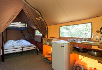 Innenansicht eines kanadischen Safarizelts mit Etagenbett und Küchenbereich im Huttopia Lagoa de Óbidos, Portugal.