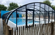Overdækket swimmingpool med glasstruktur og træhegn ved Camping Seasonova du Chêne i Pays de la Loire, Frankrig.