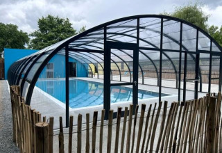 Piscina coperta con struttura in vetro e recinzione in legno al Camping Seasonova du Chêne, Pays de la Loire, Francia.