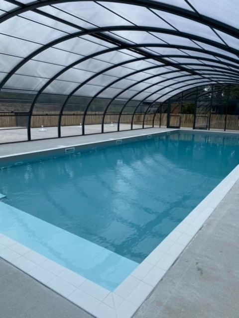Piscina cubierta bajo techo de cristal en Camping Seasonova du Chêne, parque vacacional en Pays de la Loire, Francia.
